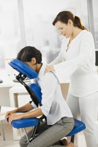 Businesswoman sitting on massage chair, getting back massage.